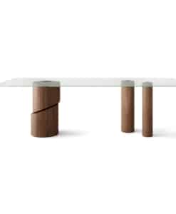 Table Ishikawa rectangulaire avec plateau en verre transparent et trois pieds cylindriques en frêne teinté noyer, dont un grand avec une découpe diagonale.